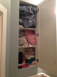 Three shelves with towels in total array and at risk to fall out once the door opens.