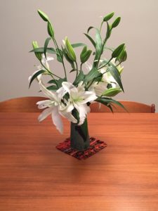 white bouqet of lilies in a vase on wooded table