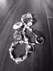 black and white image of piled on jewelry such as necklaces, rings and pins.